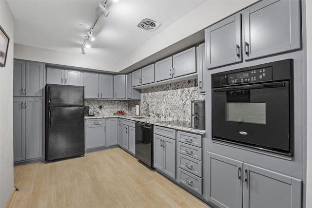 2222 1st Ave NE Unit 107, Cedar Rapids, IA 52402 - kitchen featuring black appliances, gray cabinetry, light wood-type flooring, decorative backsplash, and light stone countertops