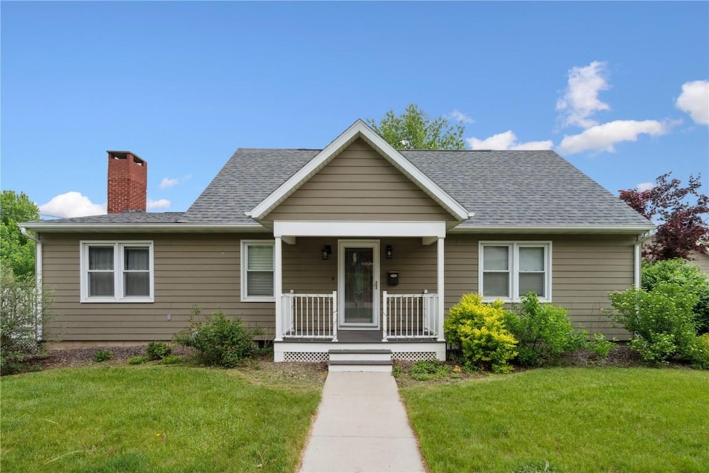 115 3rd St NE, Mount Vernon, IA 52314 - bungalow-style home featuring a porch, a chimney, a front yard, and a shingled roof