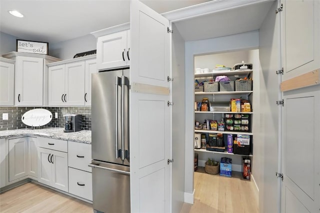 2925 Pine Hill Trce, Coralville, IA 52241 - kitchen featuring freestanding refrigerator, light wood-style floors, white cabinetry, backsplash, and recessed lighting