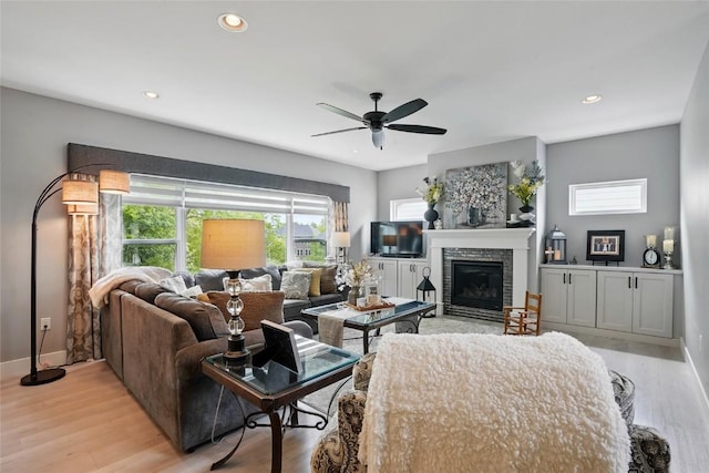 2925 Pine Hill Trce, Coralville, IA 52241 - living room featuring light wood finished floors, ceiling fan, a glass covered fireplace, baseboards, and recessed lighting