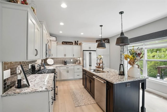 2925 Pine Hill Trce, Coralville, IA 52241 - kitchen featuring appliances with stainless steel finishes, a sink, backsplash, light wood-style floors, and an island with sink