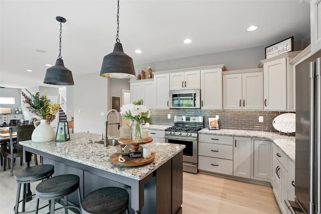 2925 Pine Hill Trce, Coralville, IA 52241 - kitchen with appliances with stainless steel finishes, tasteful backsplash, white cabinetry, an island with sink, and hanging light fixtures