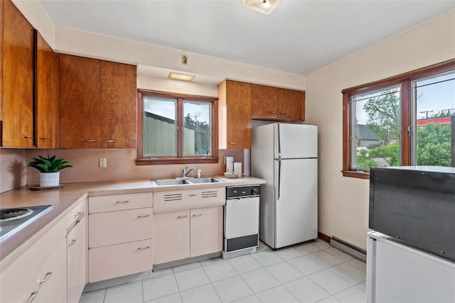 100 E Welsh St, Williamsburg, IA 52361 - kitchen with freestanding refrigerator, a sink, light countertops, a baseboard radiator, and white cabinetry
