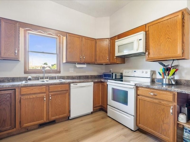 433 S Iowa St, Solon, IA 52333 - kitchen featuring white appliances, brown cabinetry, dark countertops, and light wood-style flooring