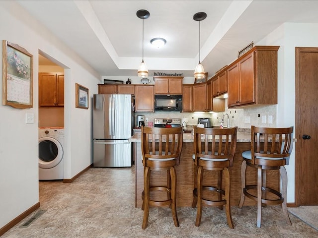 4408 Hastings Dr, Marion, IA 52302 - kitchen with stainless steel appliances, washer / dryer, brown cabinetry, a peninsula, and baseboards