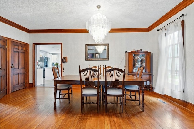 205 S Ford St, Anamosa, IA 52205 - dining area with a chandelier, wood-type flooring, a textured ceiling, and crown molding