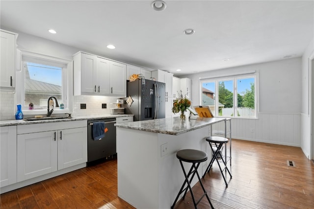 205 S Ford St, Anamosa, IA 52205 - kitchen featuring dishwasher, black refrigerator with ice dispenser, a breakfast bar area, wainscoting, and a sink