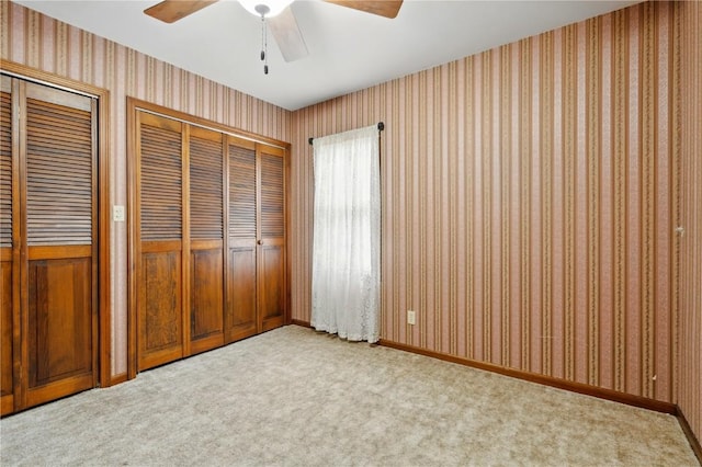 205 S Ford St, Anamosa, IA 52205 - unfurnished bedroom featuring multiple closets, wallpapered walls, light colored carpet, a ceiling fan, and baseboards