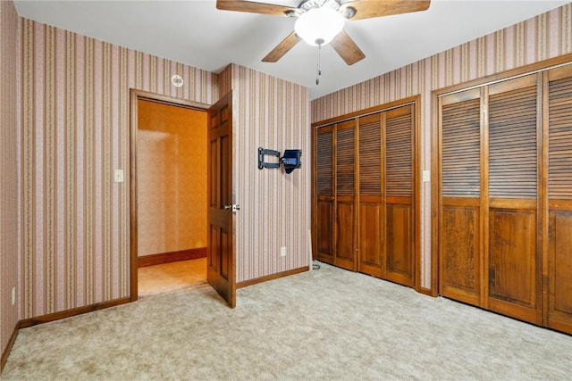 205 S Ford St, Anamosa, IA 52205 - unfurnished bedroom with multiple closets, wallpapered walls, carpet flooring, baseboards, and a ceiling fan