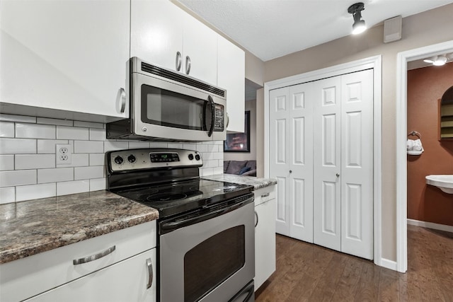 3051 Wayne Ave Unit 64, Iowa City, IA 52240 - kitchen featuring appliances with stainless steel finishes, white cabinetry, dark wood finished floors, tasteful backsplash, and dark stone countertops