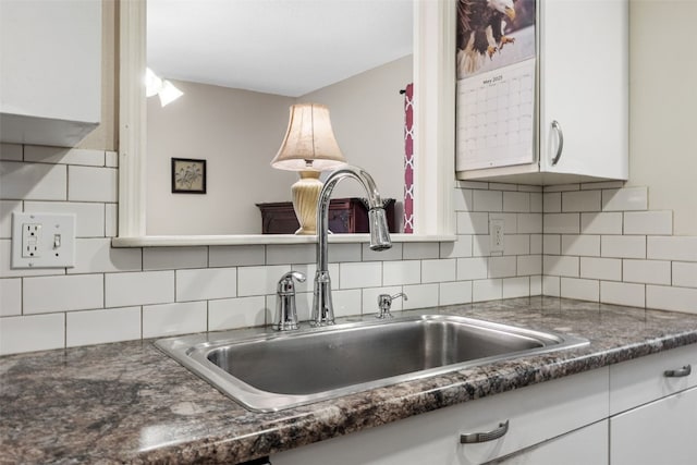 3051 Wayne Ave Unit 64, Iowa City, IA 52240 - kitchen view of a sink, white cabinetry, dark countertops, and backsplash