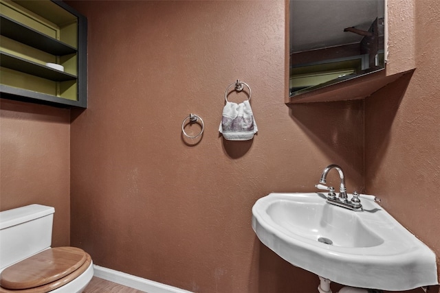 3051 Wayne Ave Unit 64, Iowa City, IA 52240 - half bathroom with a sink, toilet, wood finished floors, and baseboards