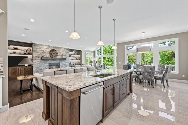 6712 Spring Grove Ct NE, Cedar Rapids, IA 52411 - kitchen featuring dishwasher, a sink, baseboards, a fireplace, and light stone countertops