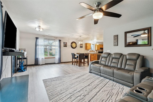 912 N St, Williamsburg, IA 52361 - living room featuring a ceiling fan, light wood-style flooring, and baseboards