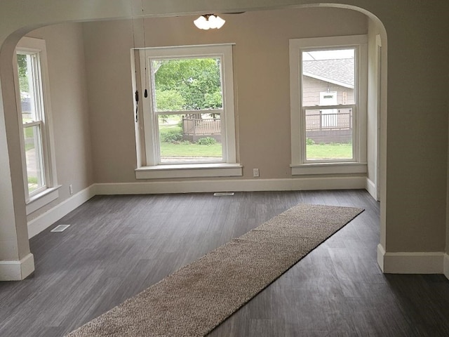 1602 11th Ave, Belle Plaine, IA 52298 - unfurnished dining area with arched walkways, baseboards, healthy amount of natural light, and wood finished floors