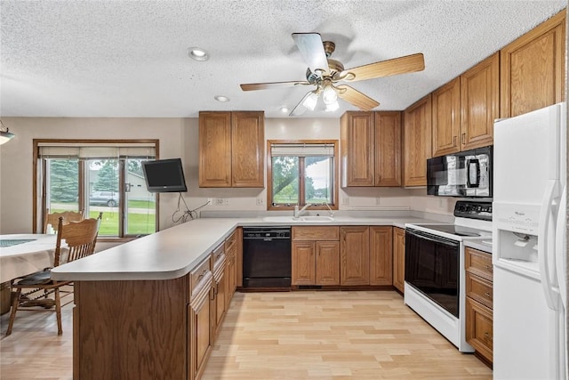 2914 Windy Ridge Rd NE, Swisher, IA 52338 - kitchen featuring black appliances, a peninsula, brown cabinetry, light wood-style flooring, and a textured ceiling