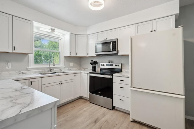 75 Jefferson Ave SW, Swisher, IA 52238 - kitchen with appliances with stainless steel finishes, a sink, light wood-style flooring, white cabinetry, and light stone counters