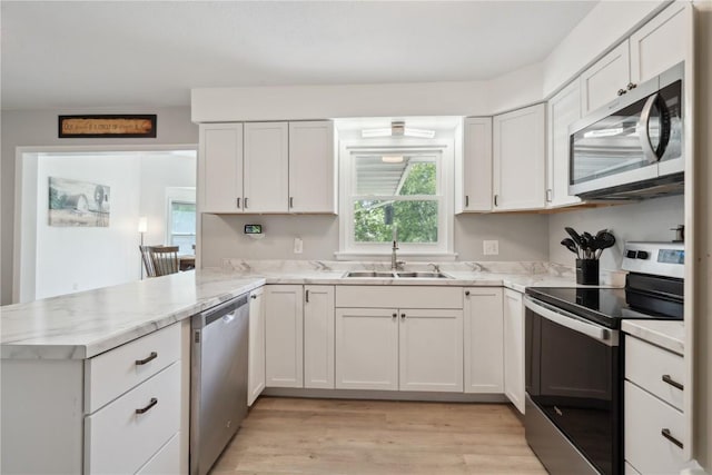 75 Jefferson Ave SW, Swisher, IA 52238 - kitchen featuring stainless steel appliances, a sink, a peninsula, light wood finished floors, and white cabinets