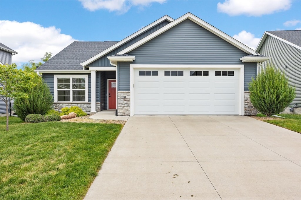 9026 Grand Oaks Dr, Cedar Rapids, IA 52402 - view of front of property featuring stone siding, a front lawn, an attached garage, and driveway
