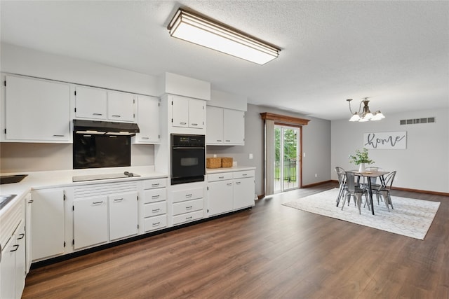 1206 W State St, Williamsburg, IA 52361 - kitchen featuring black oven, a chandelier, white cabinetry, light countertops, and dark wood-type flooring
