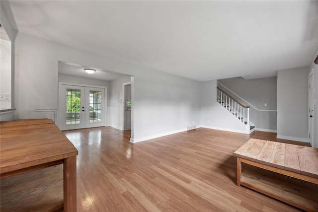 1220 Northwood Ln, Muscatine, IA 52761 - living room with light wood-style flooring, stairs, french doors, and baseboards