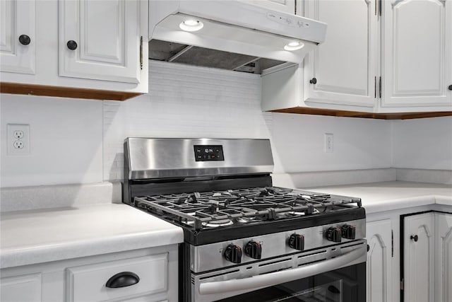 1220 Northwood Ln, Muscatine, IA 52761 - kitchen with stainless steel gas stove, under cabinet range hood, white cabinetry, light countertops, and decorative backsplash