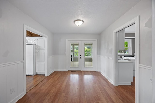 1220 Northwood Ln, Muscatine, IA 52761 - foyer with french doors, a wainscoted wall, plenty of natural light, wood finished floors, and a textured ceiling