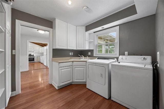 1220 Northwood Ln, Muscatine, IA 52761 - laundry room featuring independent washer and dryer, light wood finished floors, and cabinet space
