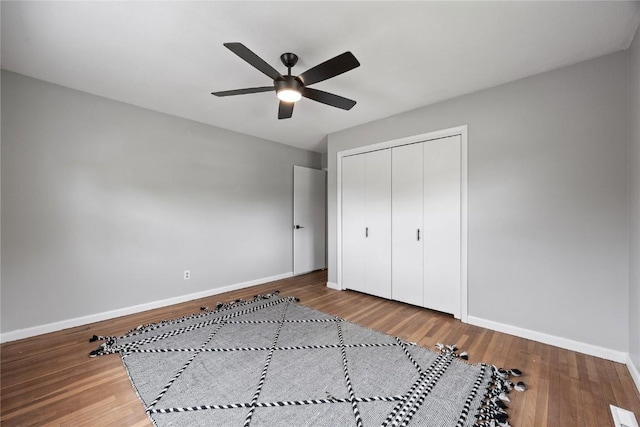 1220 Northwood Ln, Muscatine, IA 52761 - unfurnished bedroom with baseboards, wood finished floors, a closet, and a ceiling fan