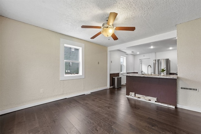 1298 14th Ave, Marion, IA 52302 - unfurnished living room featuring a textured ceiling, ceiling fan, baseboards, a textured wall, and dark wood finished floors