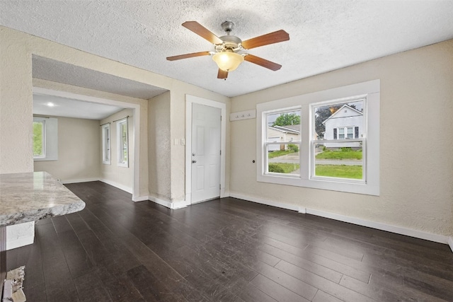 1298 14th Ave, Marion, IA 52302 - unfurnished living room featuring dark wood-style floors, baseboards, a textured ceiling, a ceiling fan, and a textured wall
