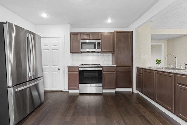1298 14th Ave, Marion, IA 52302 - kitchen with appliances with stainless steel finishes, a sink, dark wood-type flooring, decorative backsplash, and light stone counters