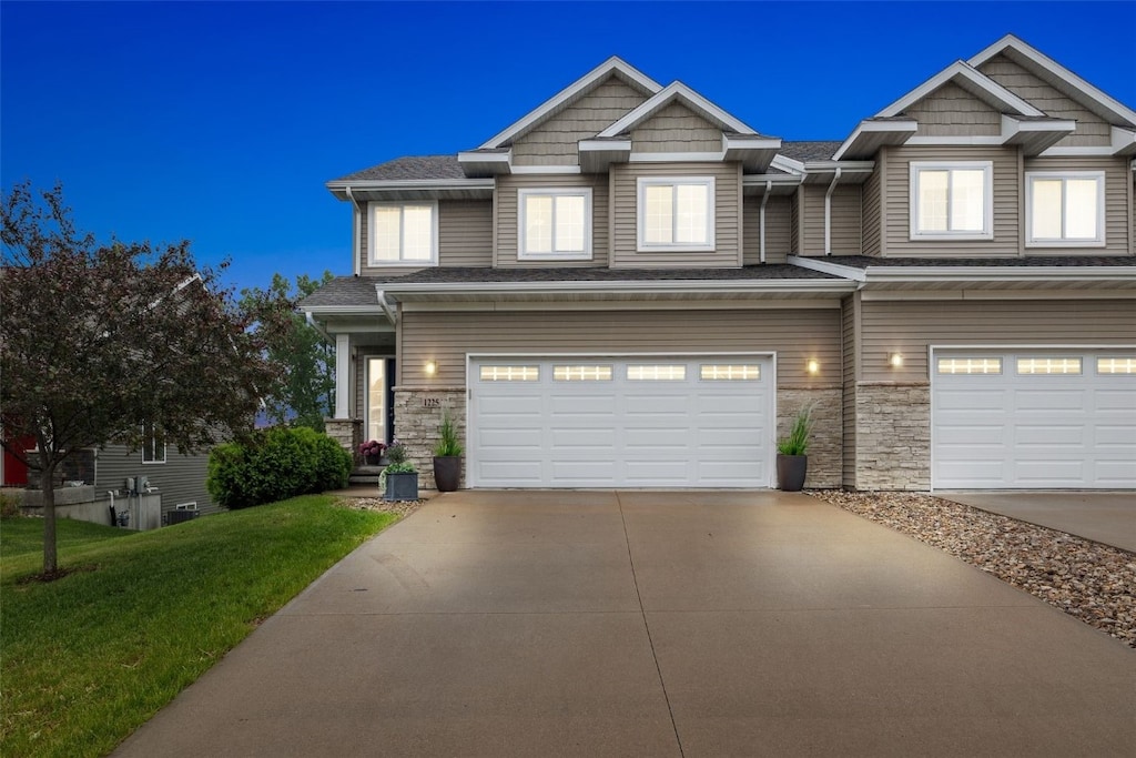 1225 Daisy Cir, North Liberty, IA 52317 - craftsman house with a garage, concrete driveway, stone siding, and a front yard