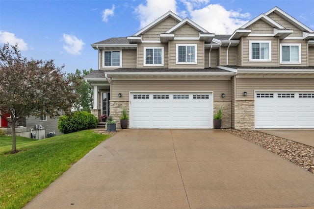 1225 Daisy Cir, North Liberty, IA 52317 - craftsman house featuring a garage, driveway, a front yard, and stone siding