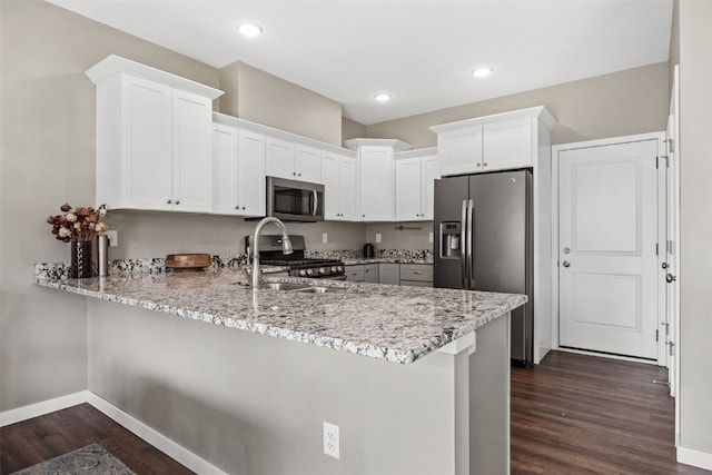 1225 Daisy Cir, North Liberty, IA 52317 - kitchen with appliances with stainless steel finishes, dark wood finished floors, a peninsula, baseboards, and light stone countertops