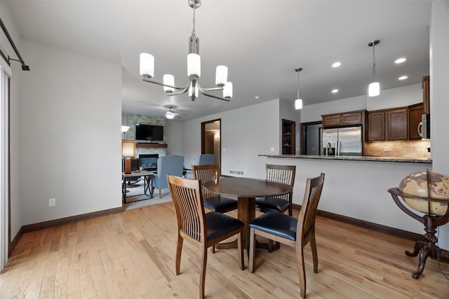 2913 Caspian Rd, Hiawatha, IA 52233 - dining space featuring a large fireplace, a chandelier, recessed lighting, light wood-style floors, and baseboards