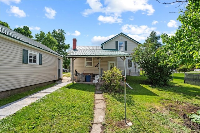 405 6th Ave, Clarence, IA 52216 - back of house featuring a lawn, a chimney, and metal roof