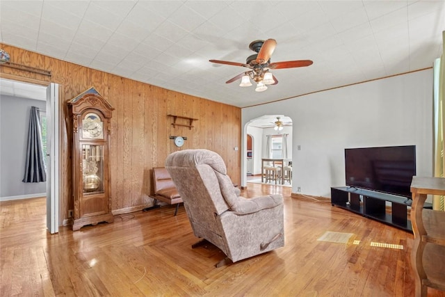 405 6th Ave, Clarence, IA 52216 - living room featuring ceiling fan, arched walkways, wooden walls, and baseboards
