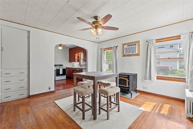 405 6th Ave, Clarence, IA 52216 - dining area featuring a wood stove, a ceiling fan, arched walkways, and light wood-style flooring