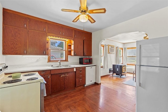 405 6th Ave, Clarence, IA 52216 - kitchen featuring white appliances, radiator heating unit, a wood stove, a sink, and a ceiling fan