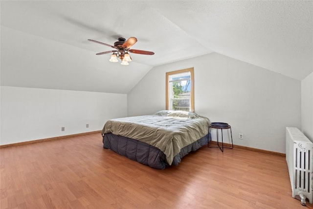 405 6th Ave, Clarence, IA 52216 - bedroom with radiator heating unit, light wood-style floors, baseboards, vaulted ceiling, and ceiling fan
