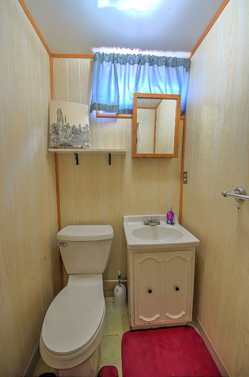 1139 H Ave NE, Cedar Rapids, IA 52402 - half bathroom with vanity, toilet, and wooden walls