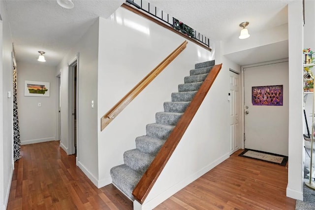 215 40th St Dr SE Unit 304, Cedar Rapids, IA 52403 - stairs with wood finished floors, baseboards, and a textured ceiling