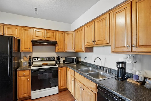 215 40th St Dr SE Unit 304, Cedar Rapids, IA 52403 - kitchen featuring black appliances, under cabinet range hood, a sink, dark countertops, and wood finished floors