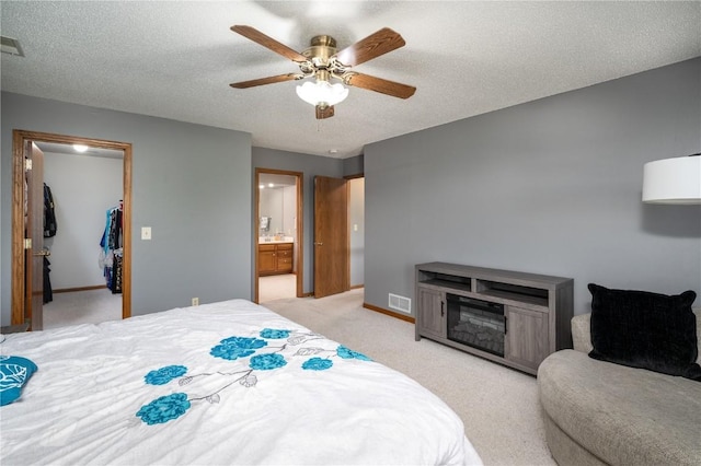 6919 Rockingham Dr SW, Cedar Rapids, IA 52404 - bedroom with a spacious closet, light colored carpet, a textured ceiling, baseboards, and a ceiling fan