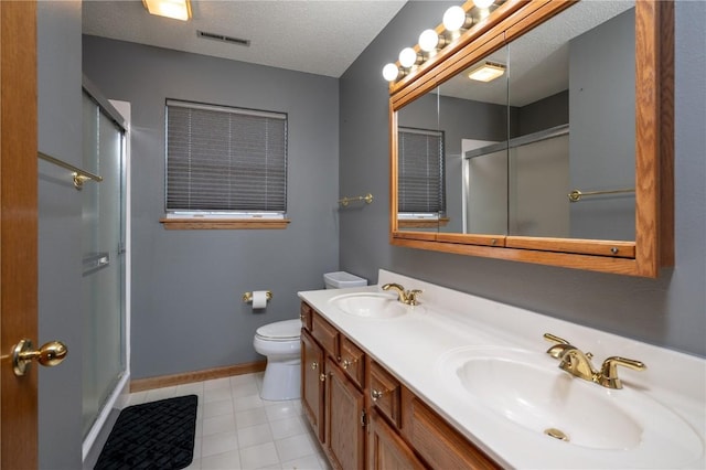 6919 Rockingham Dr SW, Cedar Rapids, IA 52404 - bathroom with a shower with door, double vanity, toilet, baseboards, and a textured ceiling