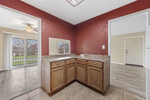 5712 Golden Ct NE Unit 60, Cedar Rapids, IA 52402 - kitchen with a textured wall, brown cabinets, light wood-style flooring, and a ceiling fan