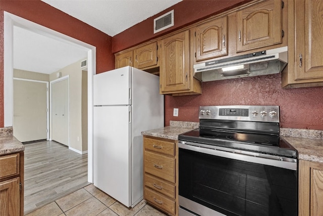 5712 Golden Ct NE Unit 60, Cedar Rapids, IA 52402 - kitchen with under cabinet range hood, stainless steel electric stove, freestanding refrigerator, light countertops, and light tile patterned floors