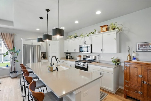 927 Summit Ct, Tiffin, IA 52340 - kitchen with appliances with stainless steel finishes, a breakfast bar, a sink, light wood-type flooring, and light countertops