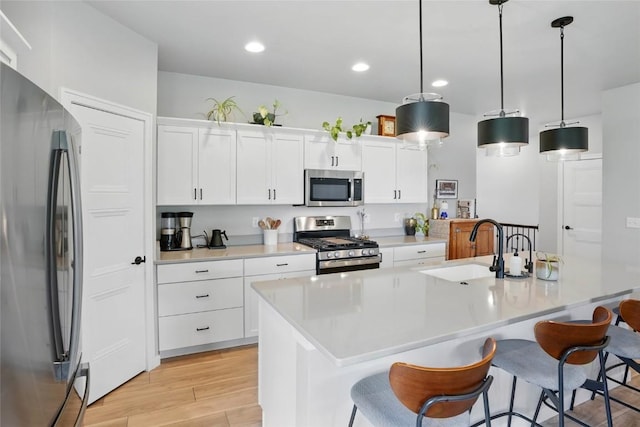927 Summit Ct, Tiffin, IA 52340 - kitchen with stainless steel appliances, a sink, a kitchen breakfast bar, light wood-style flooring, and light countertops